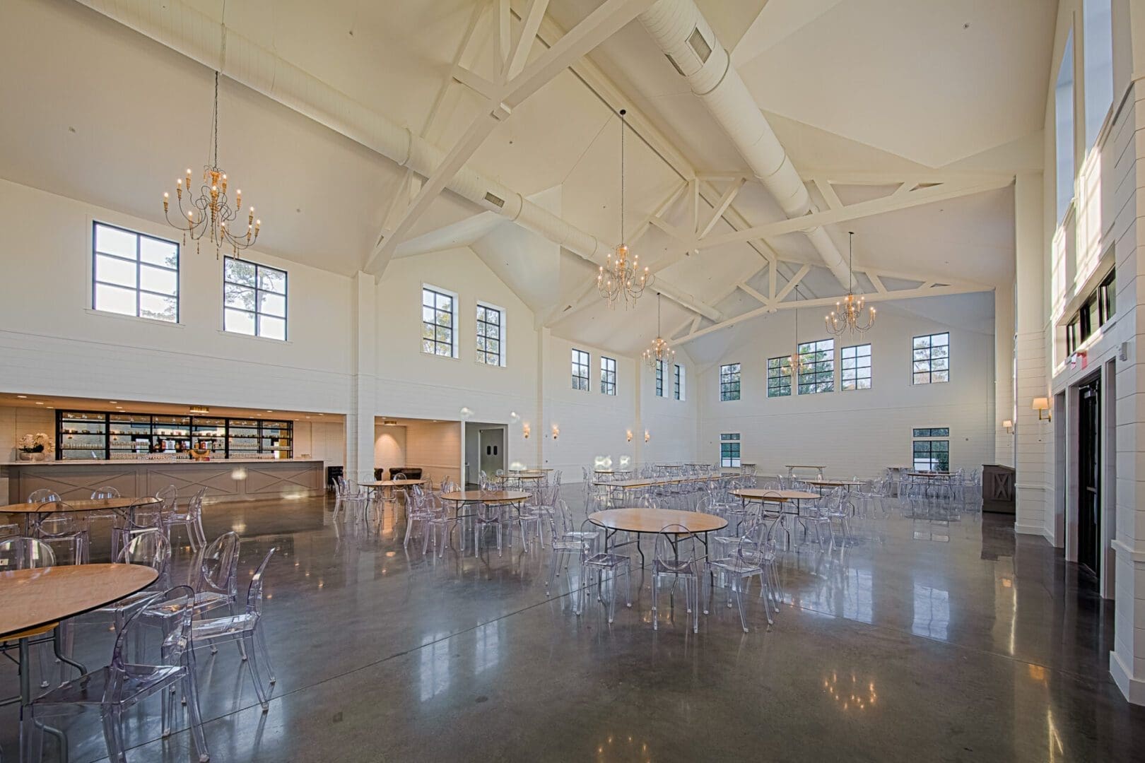 Spacious event hall with chandeliers and tables.