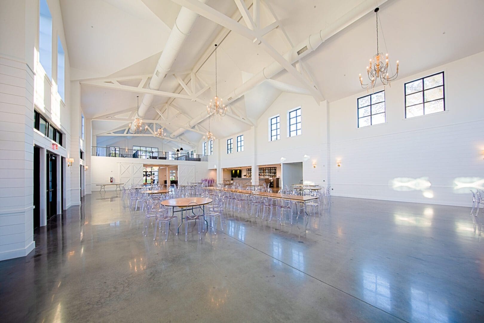 Spacious event hall with chandeliers and windows.