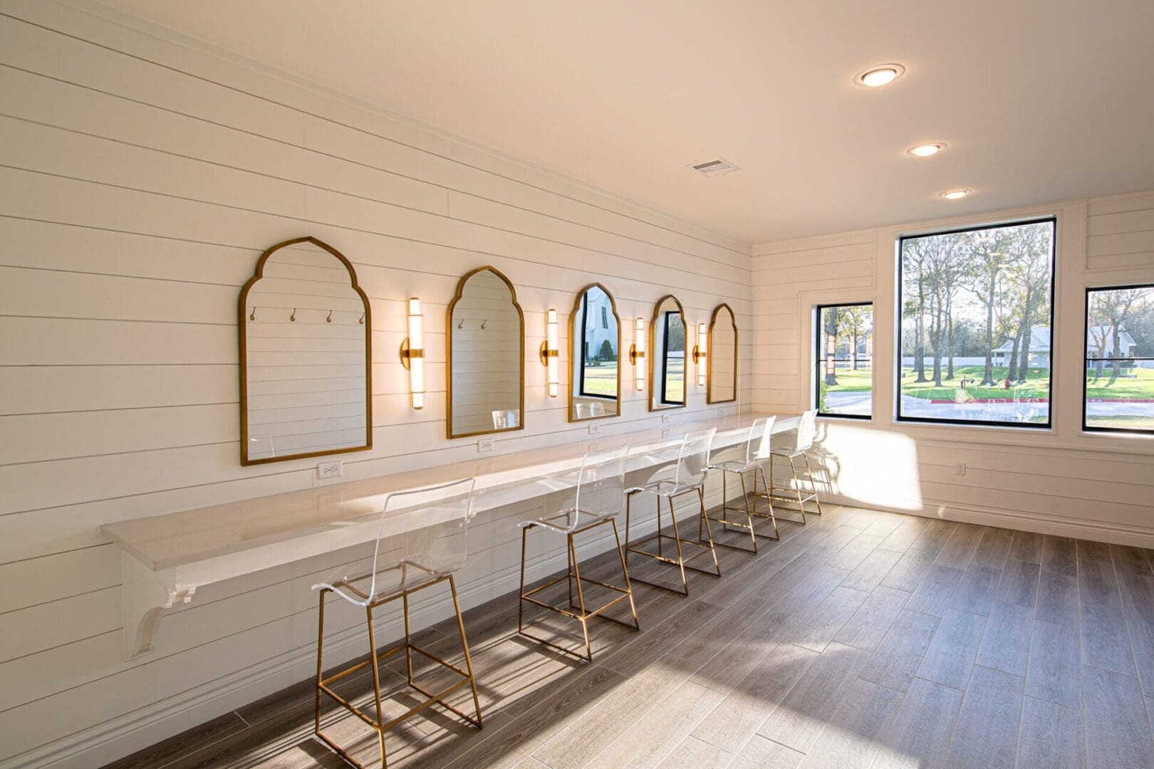 Modern vanity area with mirrors and chairs.