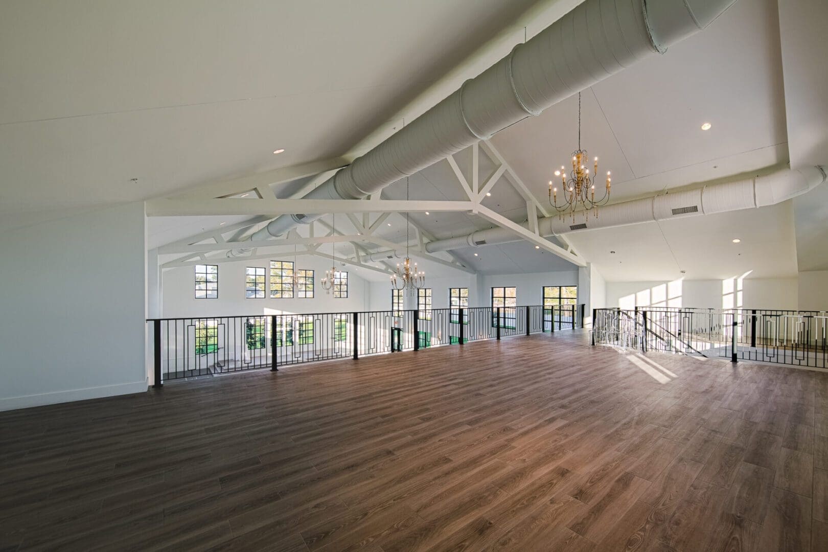 Spacious loft with chandeliers and wooden floor.