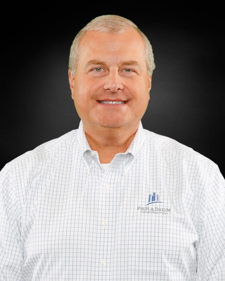 Smiling man in checkered shirt, black background.
