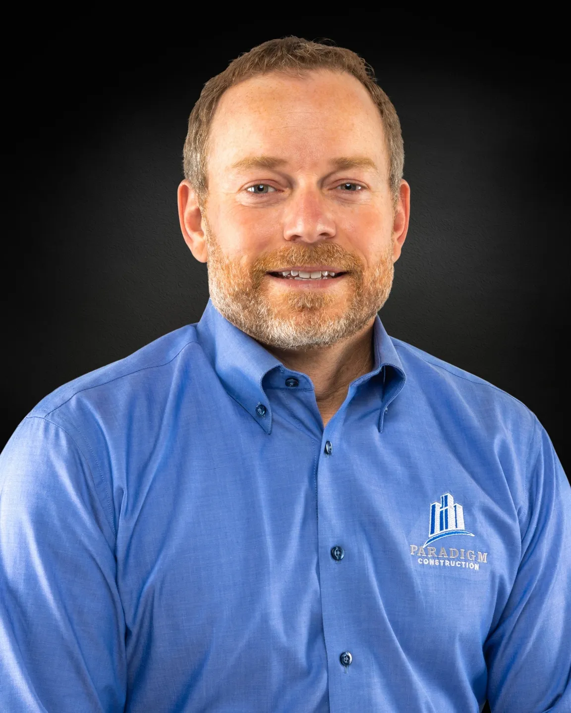 Man in blue shirt, dark background.