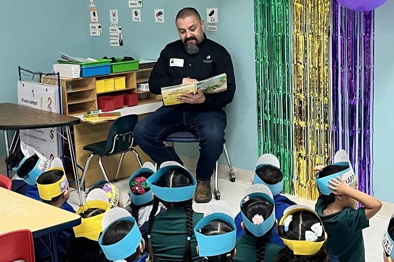 Man reading book to children in classroom.