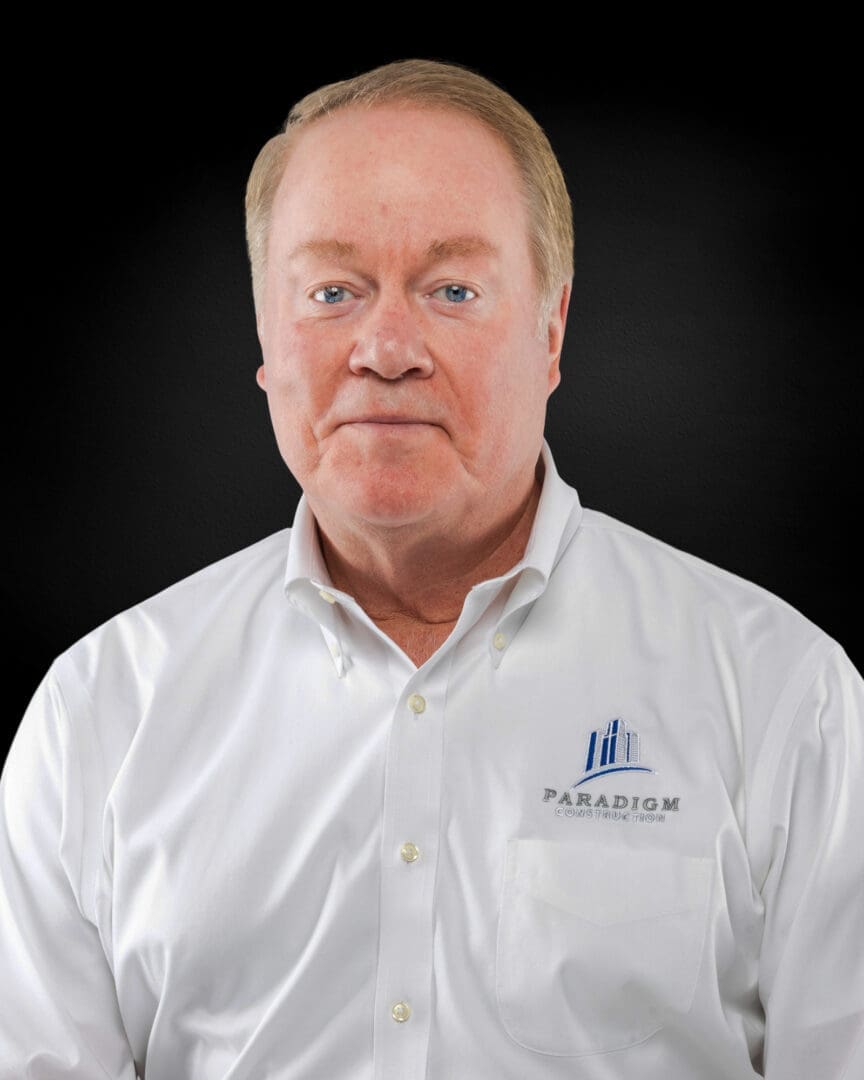 Man in white Paradigm-branded shirt, smiling.